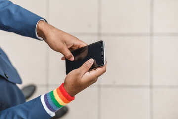 closeup of african american arms with LGBT bracelet using mobile phone, copy space