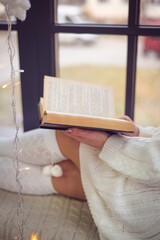 The girl is washing at the window and reading a book. A book in her hands.