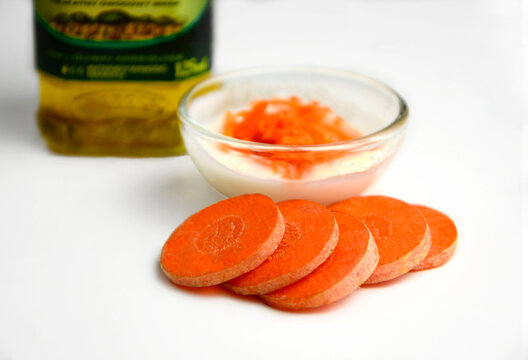 marchew w plasterkach z oliwą i jogurtem w miseczce, składniki na maseczkę upiększajacą lub sałatkę, carrot slices with yogurt and oil, ingredients for a beautifying mask or salad