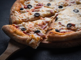 Home pizza with sausage, cheese, olive, pepper, Spices on black background. Supreme Hot Pizza
