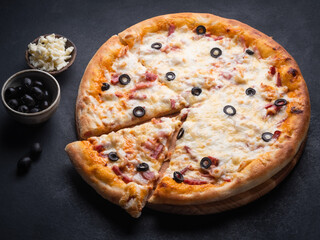 Home pizza with sausage, cheese, olive, pepper, Spices on black background. Supreme Hot Pizza