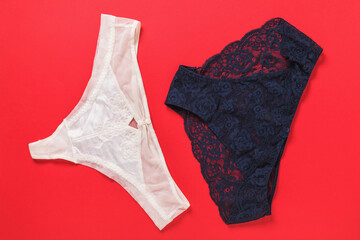 Dark blue and light beige women's panties on a red background, top view