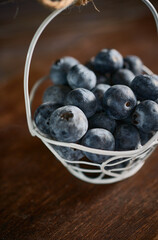 Tiny basket of blueberries on a wooden background