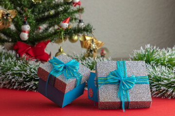 gifts with blue bow, with a Christmas tree in the background