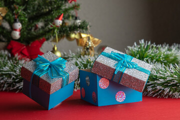 gifts with blue bow, with a Christmas tree in the background