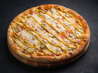 Delicious traditional homemade pizza with tomato, pepper, sausage, cheese on a black background.