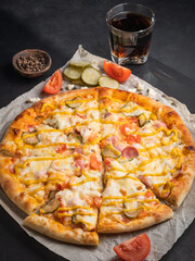 Delicious traditional homemade pizza with tomato, pepper, sausage, cheese on a black background.