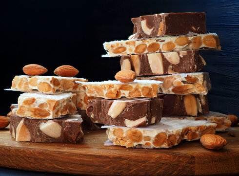 Chocolate turron with almonds, hard alicantian turron on a vintage wooden board. Close-up
