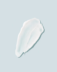 Smear of white face cream on blue background 