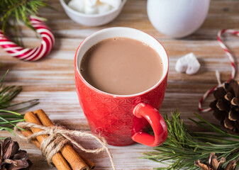 Fragrant cocoa with marshmallows in a red cup in Christmas decor on a wooden background. Merry Christmas concept.