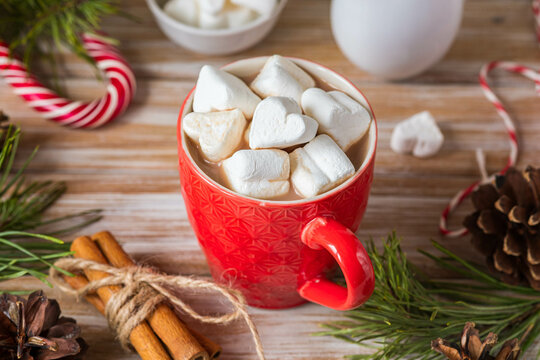 Fragrant cocoa with marshmallows in a red cup in Christmas decor on a wooden background. Merry Christmas concept.