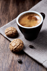 Cup of coffee with amaretti (Italian biscuits) on dark background. Close up. 