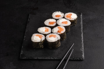 Tasty Japanese food rolls with fish and avocado on black background. Sushi menu.