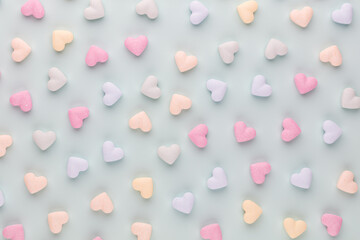 Composition with candy hearts on pastel blue background.