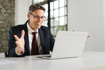 Joyful businessman celebrating his success while using a computer in the office