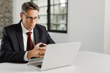 Mid adult businessman reading an e-mail on laptop in the office