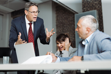 Angry boss scolding his colleague during a business meeting in the office