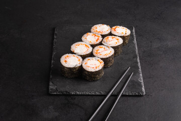 Close-up of eight sake maki rolls in plate with chopsticks on black background
