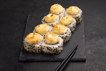 Baked rolls on the board with black  chopsticks. Delicious asian food.