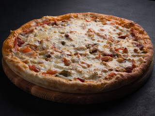 Homemade pizza with ham, cheese, tomatoes. Italian food, natural ingredients.