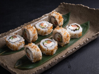 Sushi with red fish, cucumber, cream cheese on a clay plate, soy sauce, wasabi.