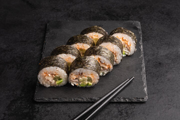 Tasty Japanese food rolls with fish and avocado on black background. Sushi menu.