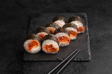 Tasty Japanese food rolls with fish and avocado on black background. Sushi menu.
