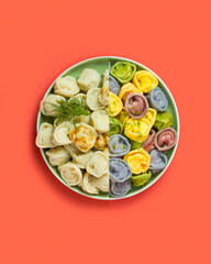 Two types of dumplings in a plate: traditional and colored, red background 
