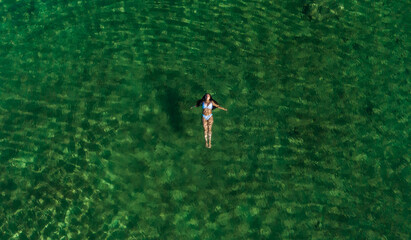 Aerial photograph of a girl swimming in one of the lagoons of Cuatrociénegas, Coahuila, Mexico. She wears a blue swimsuit that contrasts with the turquoise color of the water.