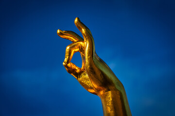 Goldene Hand vor blauem Himmel