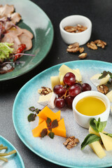 cheese plate with honey and grape on dark concrete table. dinner concept