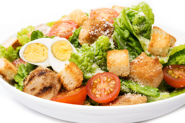 Caesar salad with chicken, croutons and parmesan in a plate isolated on a white background