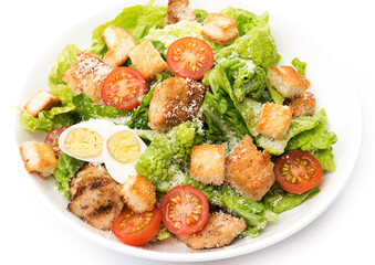 Caesar salad with chicken, croutons and parmesan in a plate isolated on a white background