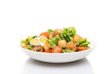 Caesar salad with chicken, croutons and parmesan in a plate isolated on a white background