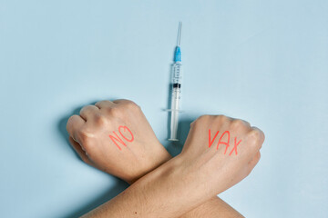 Antivaxxer crossing hands near the syringe with Covid-19 vaccine. A person refusing immunization...