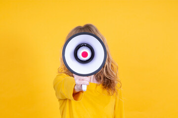 mature woman yelling with megaphone with yellow background