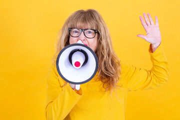 Fototapeta premium mature woman yelling with megaphone with yellow background