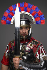Roman legionnaire posing with sword isolated on gray