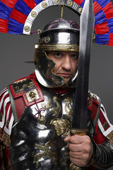 Roman legionnaire posing with sword isolated on gray