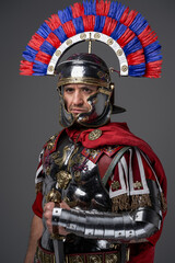 Thoughtful roman warrior dressed in steel armor and red cloak