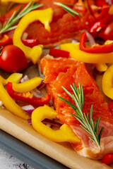 Baking sheet with cooked fish for baking, red fish Arctic char with tomatoes and peppers and rosemary on a baking sheet close-up