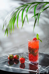 strawberry mojito with mint leaf on marble table. fresh drinks with strawberry and tropic branch on background