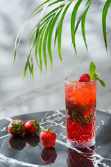 strawberry mojito with mint leaf on marble table. fresh drinks with strawberry and tropic branch on background