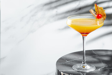 citrus and pineapple cocktail on marble table with copy space. tropical cocktail with shadow of tropical plants branch on background