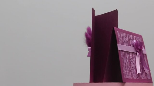 Making greeting cards. Paper blanks, ribbons and lagurus branches. Stands on a rotating stage. On white background