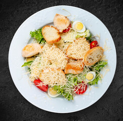 Caesar salad with chicken, egg and fresh vegetables. Isolated on a black background