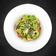 Salad with avocado and pine nuts. Isolated on a black background.