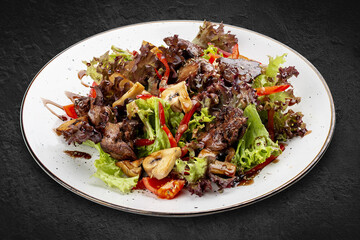 Salad with chicken liver, sweet pepper and champignons. Isolated on a black background.