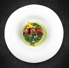 Stewed spinach with pine nuts. Isolated on a black background.