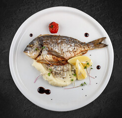 Dorado with mashed potatoes and creamy mushroom sauce. Isolated on a black background.